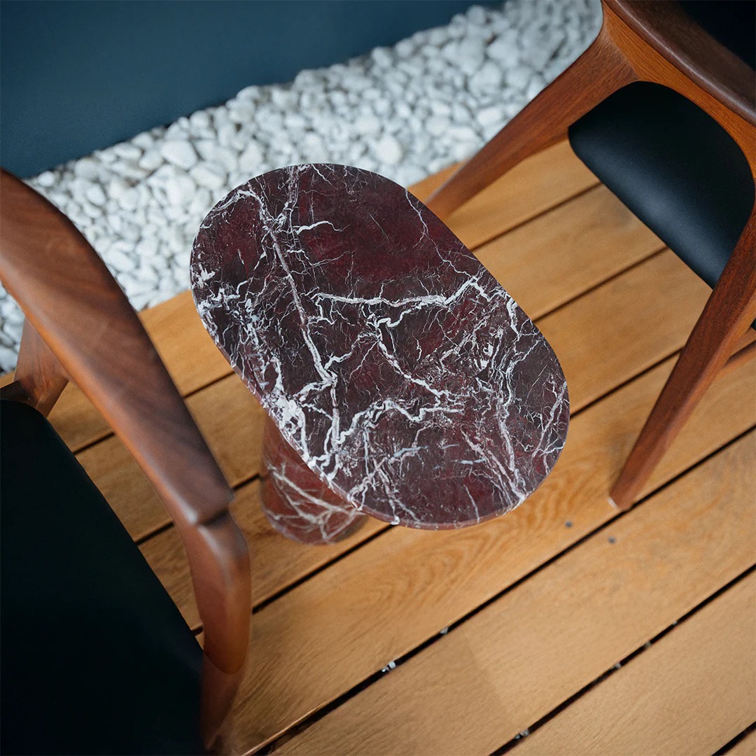 Close-up of burgundy veined marble side table next to wooden chair - luxury stone accent furniture