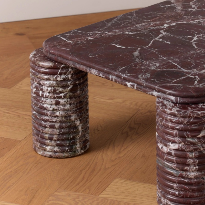 Close-up of ribbed cylindrical Rosso Levanto legs on coffee table - layered stone pattern detail